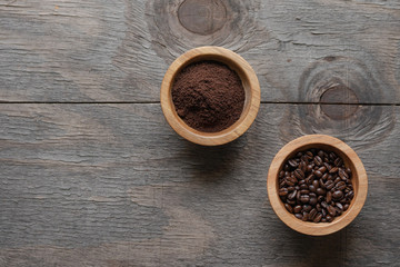 Coffee in beans and grounded coffee on wooden background, top view with copy space