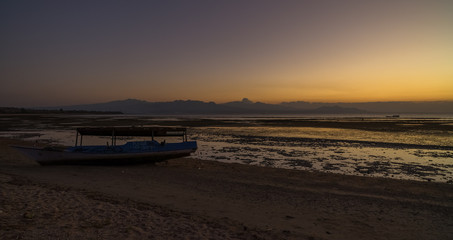 Wooden traditional boat at the beach on low tide evening sunset scene at Ai Lemak pantai in near Sumbawa Besar town