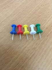 Colored push pins lie on a brown table