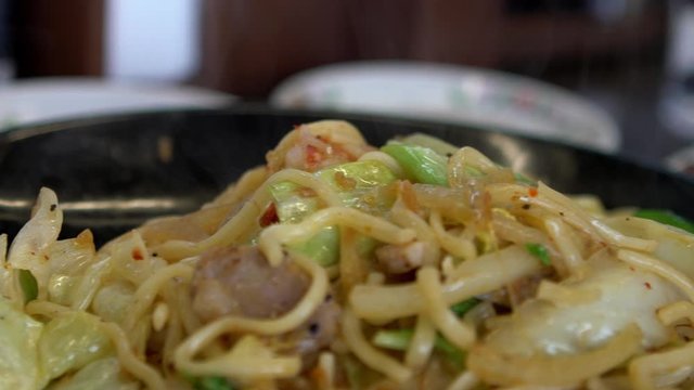 Slow motion of Yakisoba Ramen with pork belly meat and fired egg ready to eat. Asian food japan pasta noodles with vegetables and meat. Stir fried spicy noodle  -Dan