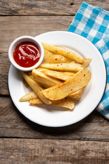 French fries with ketchup sauce on wooden background