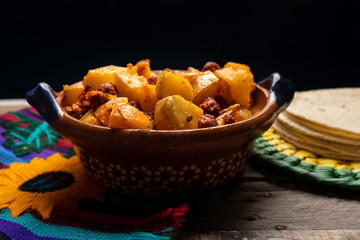 Mexican potatoes with chorizo on wooden background