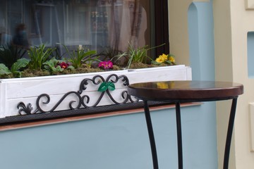 flowers on the window and a round table near the cafe