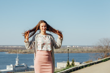 Portrait of smiling woman in a white cardigan. Laughing girl on the background of street, freedom and happiness