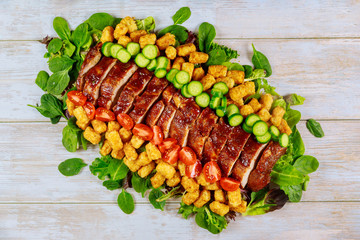 Cuts pork loin fillet serve with green salad and tomatos.