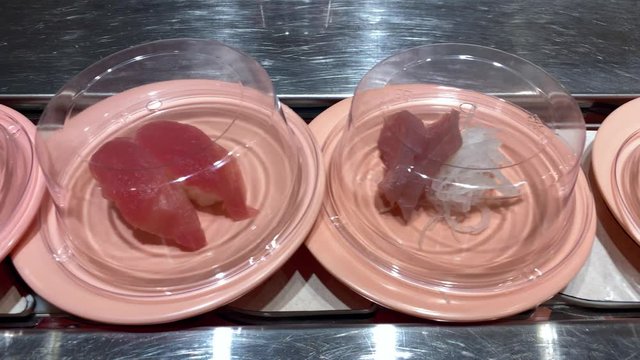 4K, Sushi on moving conveyor belt in a Japan restaurant. Traditional Kaitenzushi Japanese food. Shushi Go Round is a famous form of fast food common in Asia, also known as sushi train.-Dan