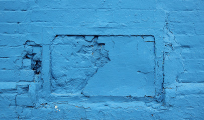 Rough wall painted in light blue color with bricks and irregular shape - background texture with...