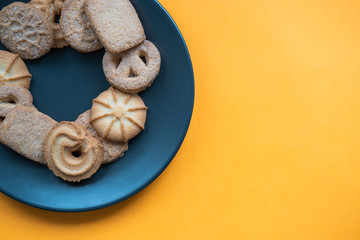 Danish cookies on a grey plate on orange background. Top view. Copy space.