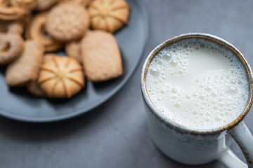 Milk mug with danish cookies in background. Close up view.