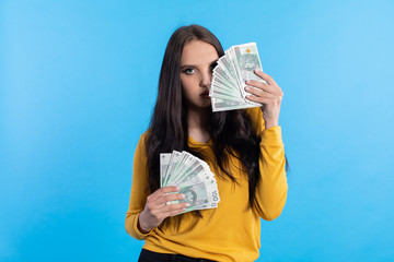 The young woman holds a fan of paper banknotes with a face value of one hundred zlotys.
