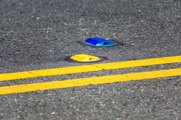 Raised yellow pavement marker separates opposing traffic lanes. The blue marker denotes a fire...