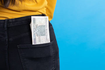 The woman is holding a bundle of 100 Polish zlotys banknotes in her back pocket.