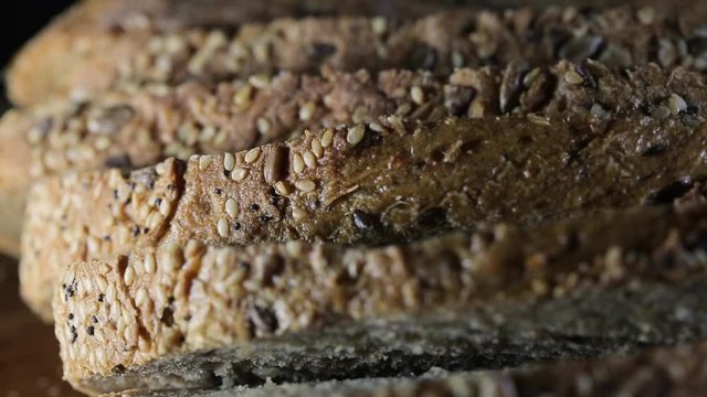 Man cutted cereal bread on a table on a dark background, close up, fullHD