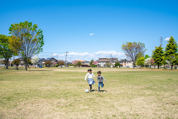 Fototapeta premium 青空の公園でサッカーをする子供