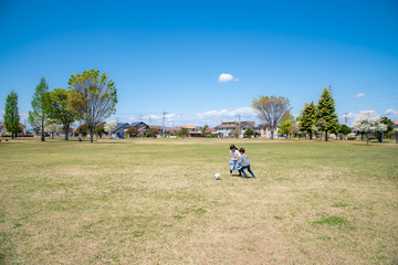青空の公園でサッカーをする子供