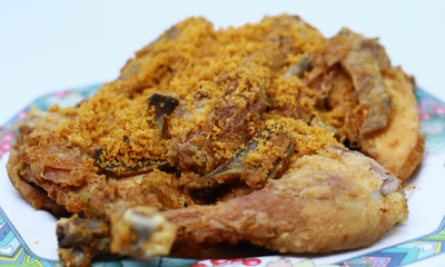 Fried chicken with crispy spiced flakes on white background. Indonesian fried chicken or ayam goreng kremes.
