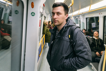 Man with a backpack in tube carriage Copenhagen, Denmark. Young caucasian man commuter in the subway, commuting, journey, underground concept. The portrait of a young male in sub