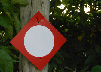 Pequeña señal de prohicion con un circulo blanco sobre fondo rojo, colocada en un arbol en el campo 