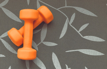 Orange dumbbell for fitness isolated on grey background
