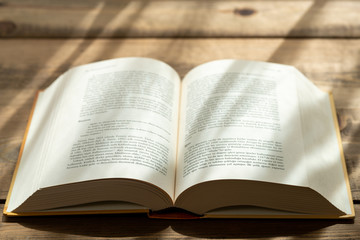 Fototapeta premium A thick book with open hardcover on a wooden floor