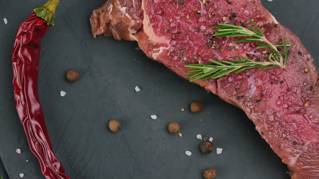 Beef sirloin raw steaks with spices on a dark table.