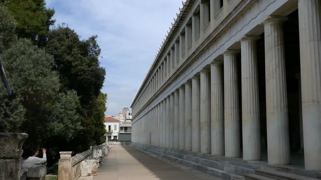 Right to left pan in the exterior length of Stoa of Attalos in Athens with Greece flag