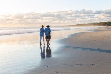 Pareja caminando por espejo de agua en una playa tranquila papa e hija mayor 