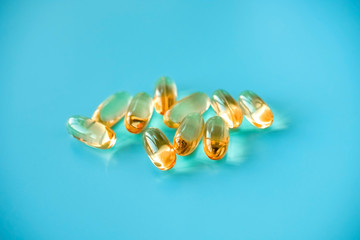 handful of omega 3 capsules on a blue background