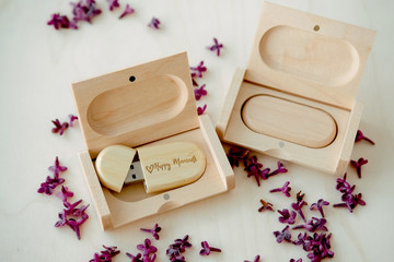Wooden brown usb flash drives with boxes with the text Happy Moments with lilac petals on a white background, data storage, beautiful feedback to client.set for the photographer, presentable set of ph