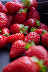 a lot of fresh juisy strawberries scatterd on a black table