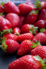 a lot of fresh juisy strawberries scatterd on a black table