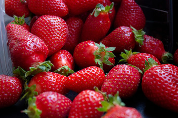 a lot of fresh juisy strawberries scatterd on a black table