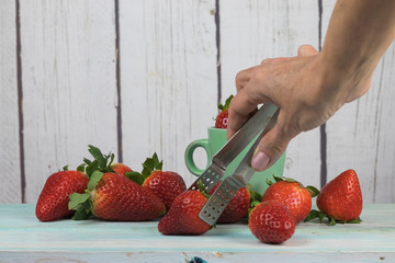 Human hand picking strawberries with pliers