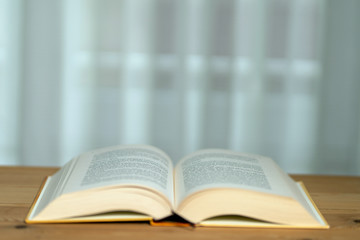 A thick book with open hardcover on a wooden floor