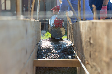 A man pours cement mortar from a bucket. Concrete foundation for home