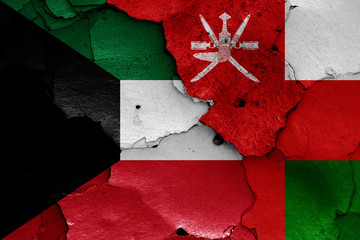 flags of Kuwait and Oman painted on cracked wall