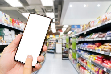 Touch screen smartphone in a hand, Blurred Supermarkets.