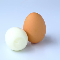 halves of boiled and raw chicken eggs on wooden rustic background. the view from the top
