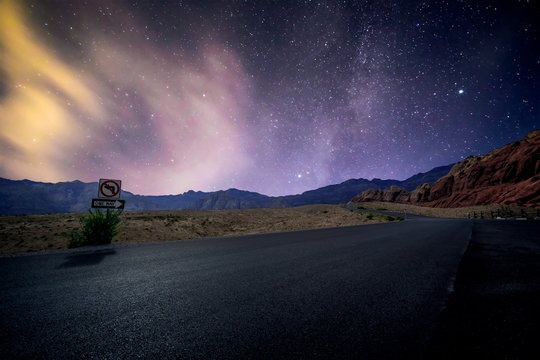 Red Rock Canyon in Las Vegas, Nevada, USA under a star lit sky glowing over the asphalt scenic byway.