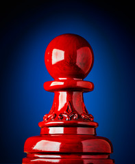 Macro image of a wooden chess pawn in red with blue and black background