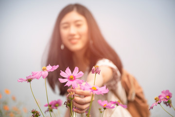 selective focus of Beautiful young woman wearing a nice dress having fun in park with flowers. Vintage scenery. Pretty asian girl with retro look 
