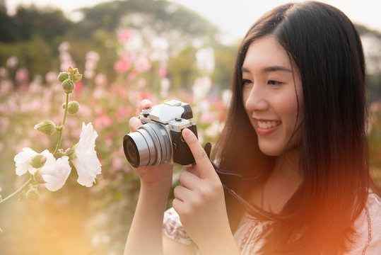 young woman taking photo with camera in a flower garden
