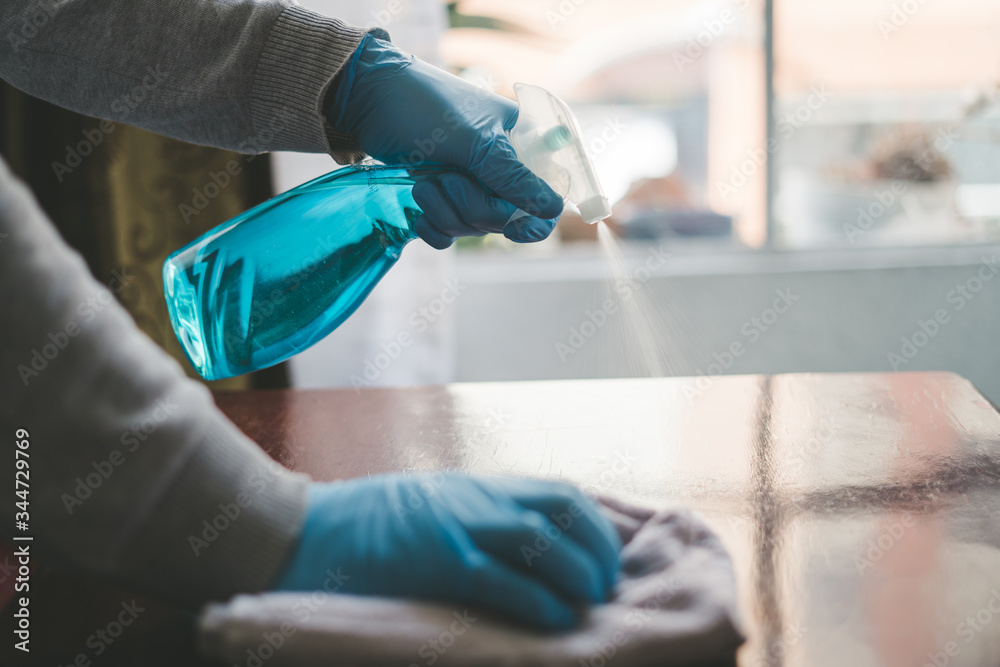 Wall mural cleaning the table with disinfectant spray, bottle washing with towels and gloves. covid-19 preventi