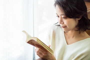 窓際で本を読む女性