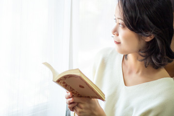 窓際で本を読む女性