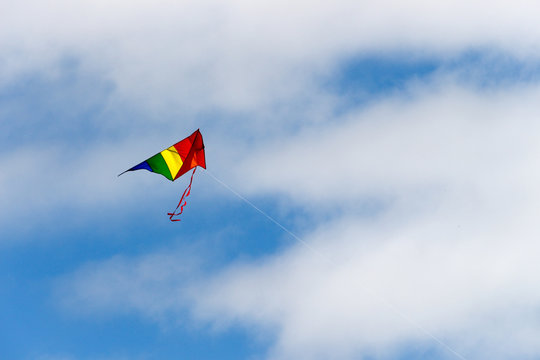 kite flying high in against a blue sky with white clouds