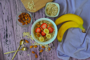 Delicious and healthy homemade milk oatmeal porridge with banana and strawberries and almonds. Food flat lay top view