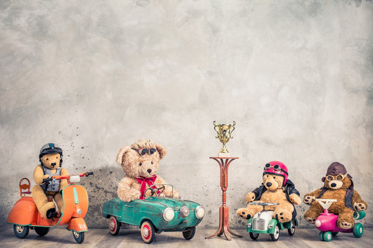 Retro Teddy Bear toys with helmets, goggles on old children's pedal  scooter, aged cars, shuttle or plane, golden trophy cup. Kids race winners and award prize concept. Vintage style filtered photo