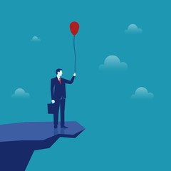 startBusinessman on a cliff above an abyss holding a balloon.