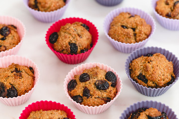 Bran muffins with dry cranberries close up in baking silicon cups on white background. Healthy food, good source of dietary fiber